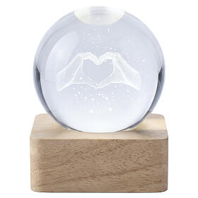 Crystal sphere with hands forming a heart, square wooden base, 2.5 in