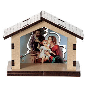 Häuschen aus Holz mit einer Szene der Heiligen Familie im Hintergrund