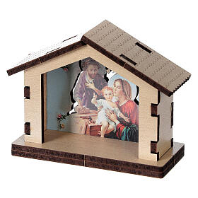 Häuschen aus Holz mit einer Szene der Heiligen Familie im Hintergrund