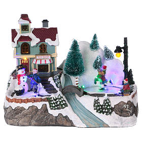 Village Noël éclairé patineurs mouvement magasin jouets 20x25x15 cm piles courant