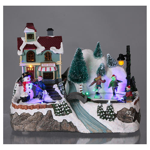 Village Noël éclairé patineurs mouvement magasin jouets 20x25x15 cm piles courant 2