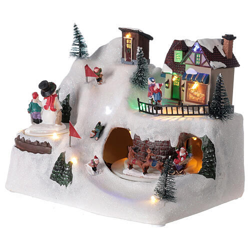 Cenário natalino em miniatura paisagem nevada com esquiadores, boneco de neve e Pai Natal, movimentos, música e luzes LED, 20x26x17 cm 3