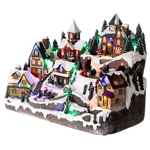Aldeia de Natal nevada em miniatura com patinadores e comboio movimento luzes LED 36x45x26 cm 3