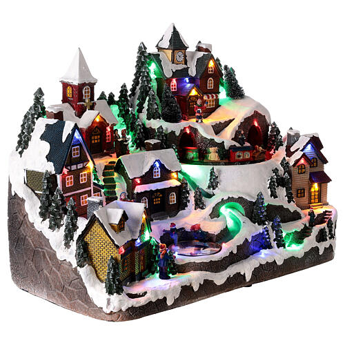 Aldeia de Natal nevada em miniatura com patinadores e comboio movimento luzes LED 36x45x26 cm 4