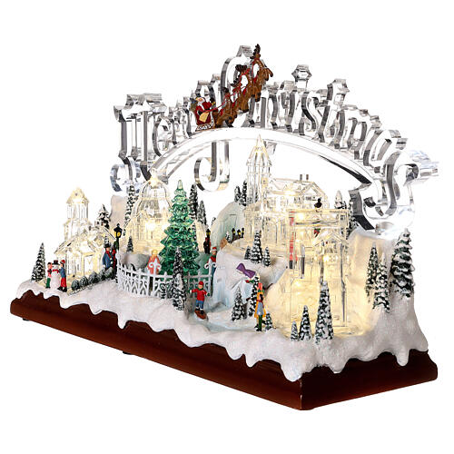 Christmas village set: clear buildings and inscription and skaters in motion 10x16x6 in 3