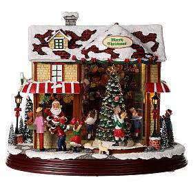 Village de Noël magasin Père Noël avec sapin en mouvement 25x30x15 cm